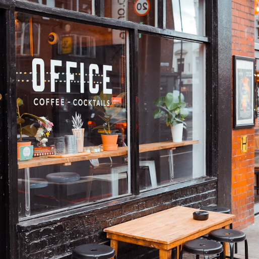 窓の外にテーブルと椅子が置いてあるカフェの外観